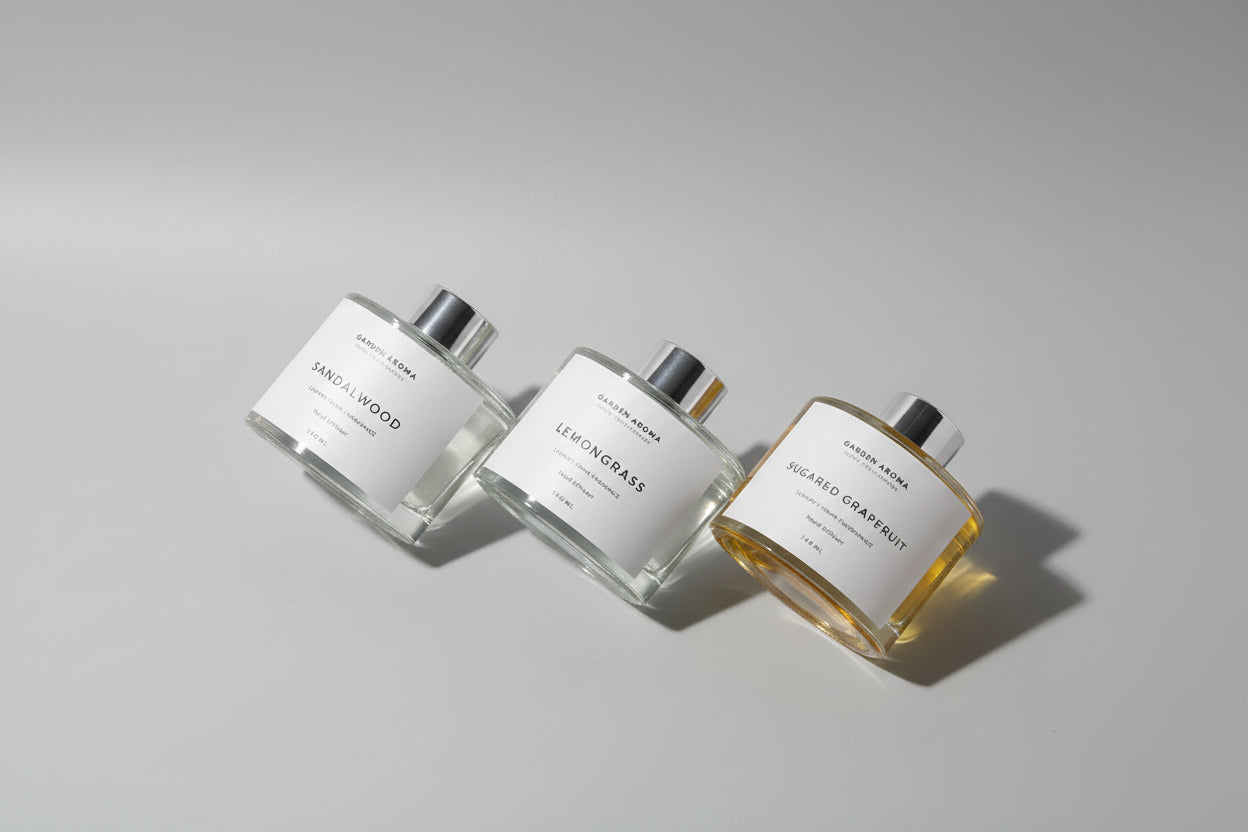 Three perfume bottles on a light gray background, Sandalwood, Lemongrass and Sugered Grapefruit.